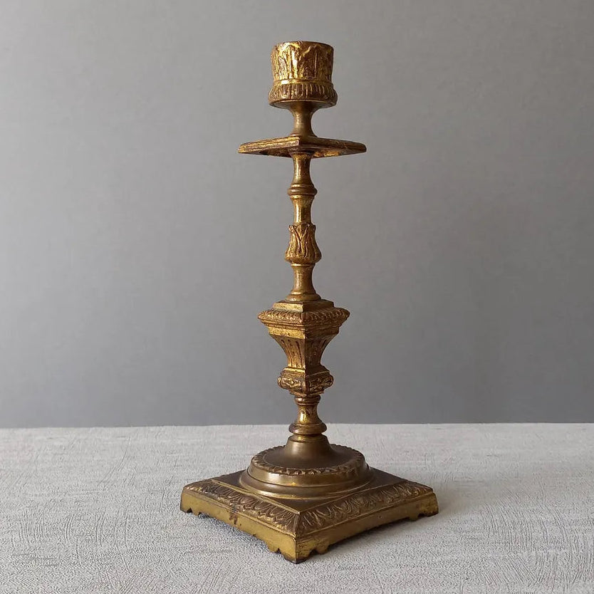 Decorative bronze candlestick on a textured surface with a gray 