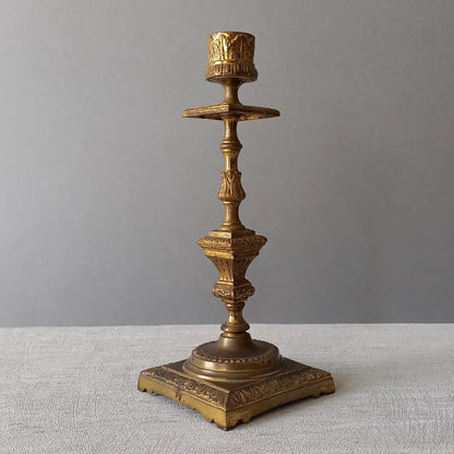 Decorative bronze candlestick on a textured surface with a gray 