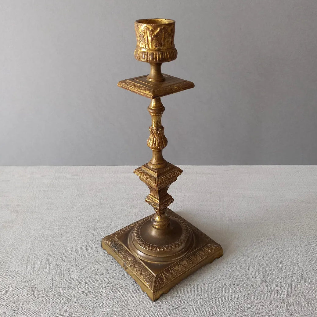 Decorative bronze candlestick on a light gray surface with a neutral background