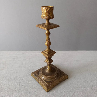 Decorative bronze candlestick on a light gray surface with a neutral background