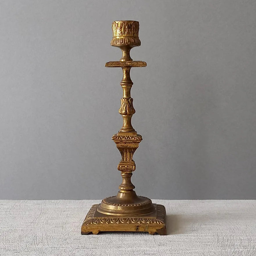 Decorative bronze candlestick on a textured surface with a gray background