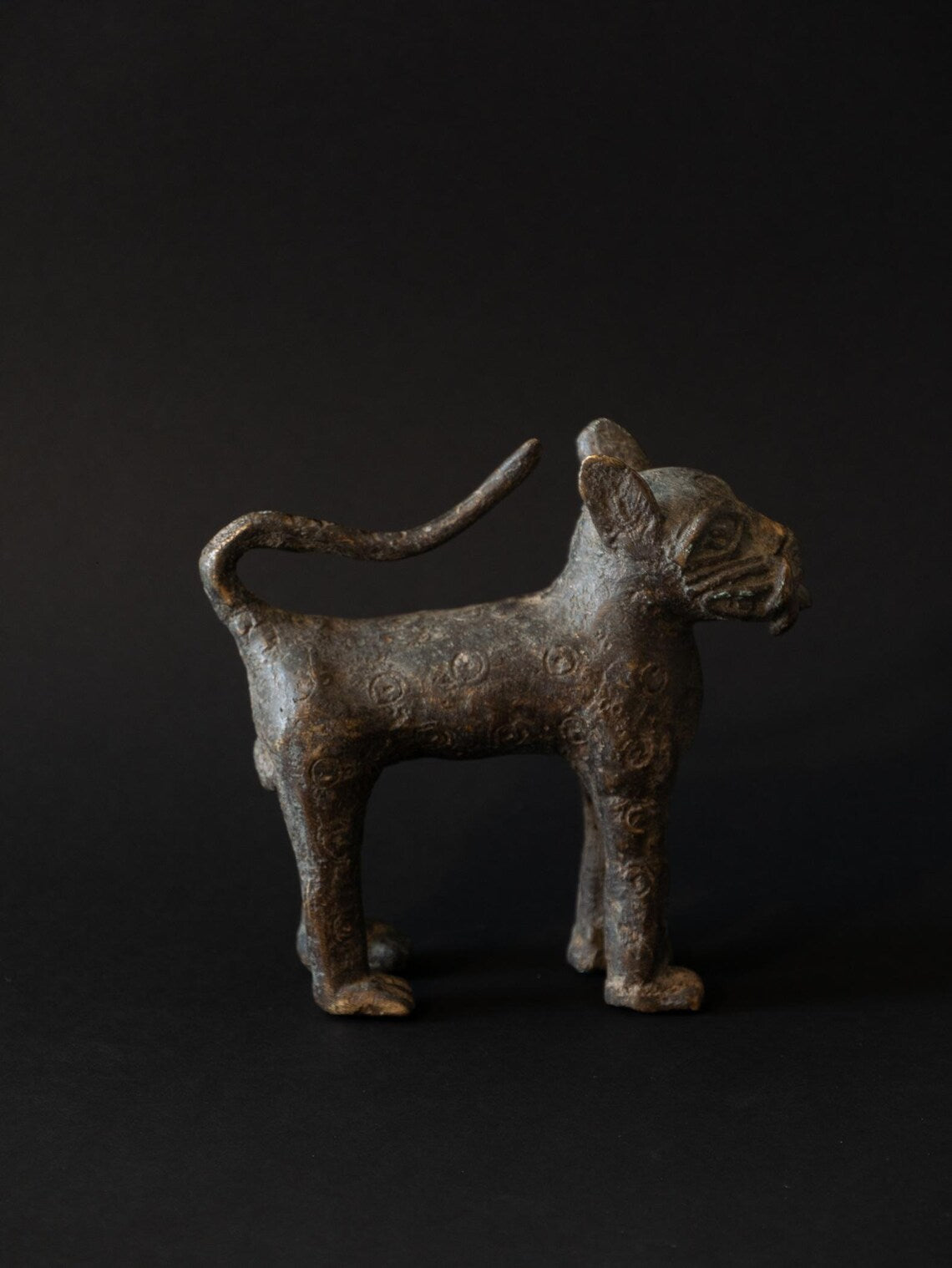 Bronze figurine of a standing animal on a black background