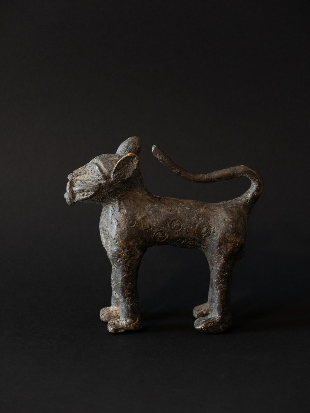 Bronze sculpture of a standing creature on a black background