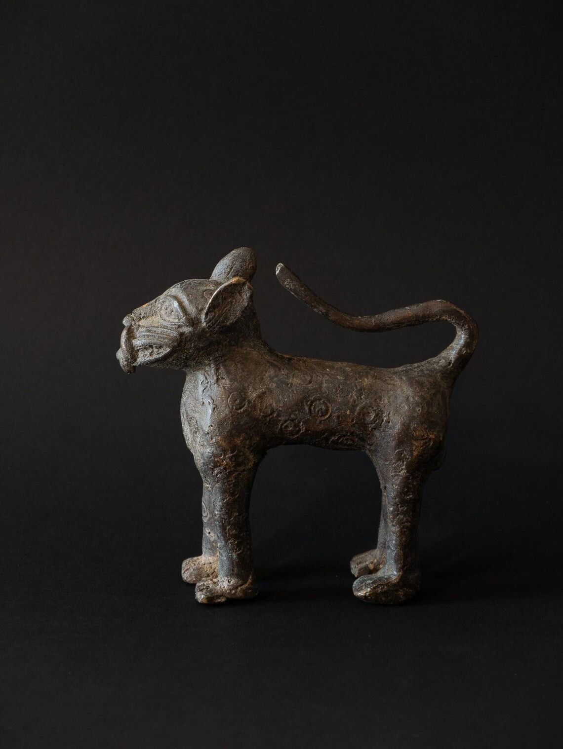 Bronze sculpture of a standing creature on a black background