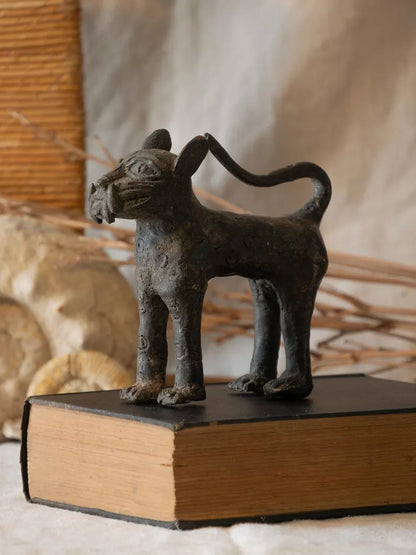 Bronze cat figurine on an open book with a blurred natural background