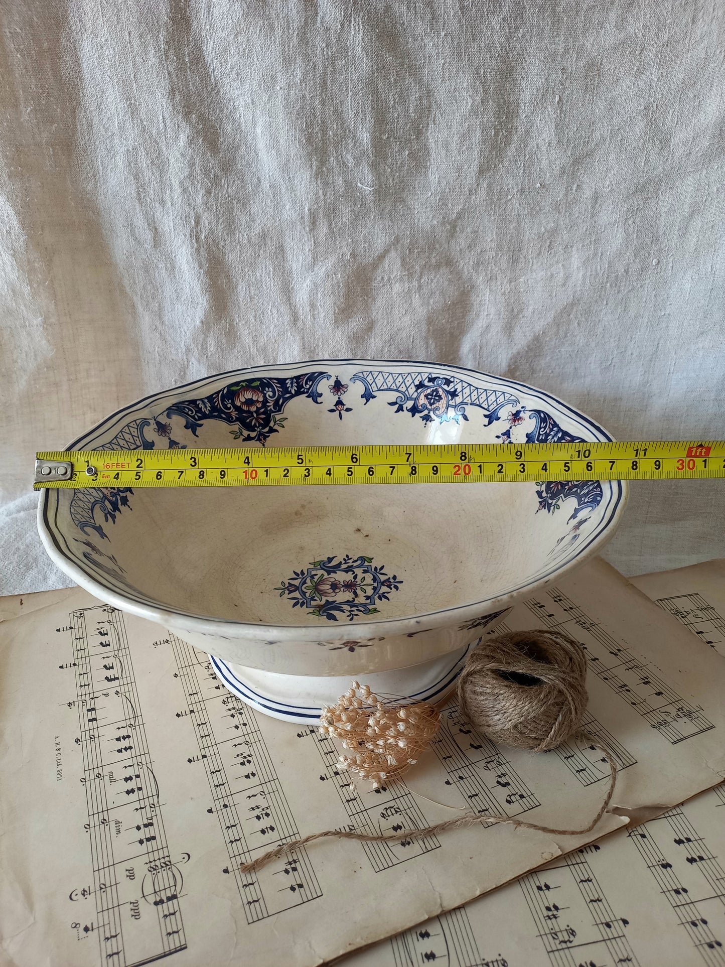 Large French antique decorative footed bowl with a stunning floral pattern in a decorative setting  with a tape measure for reference.