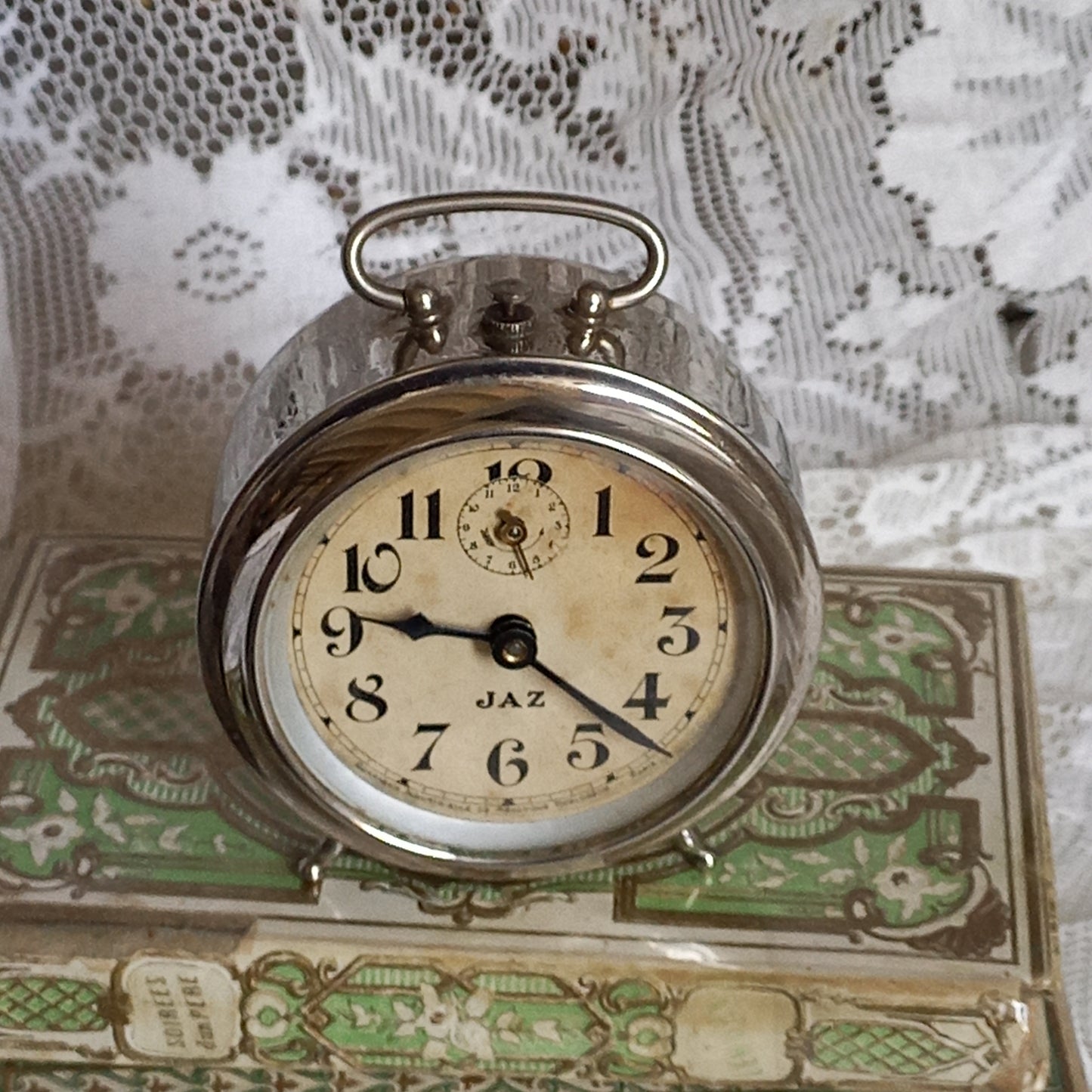 Small vintage mechanical alarm clock by French company Jaz with silver colored, chrome case