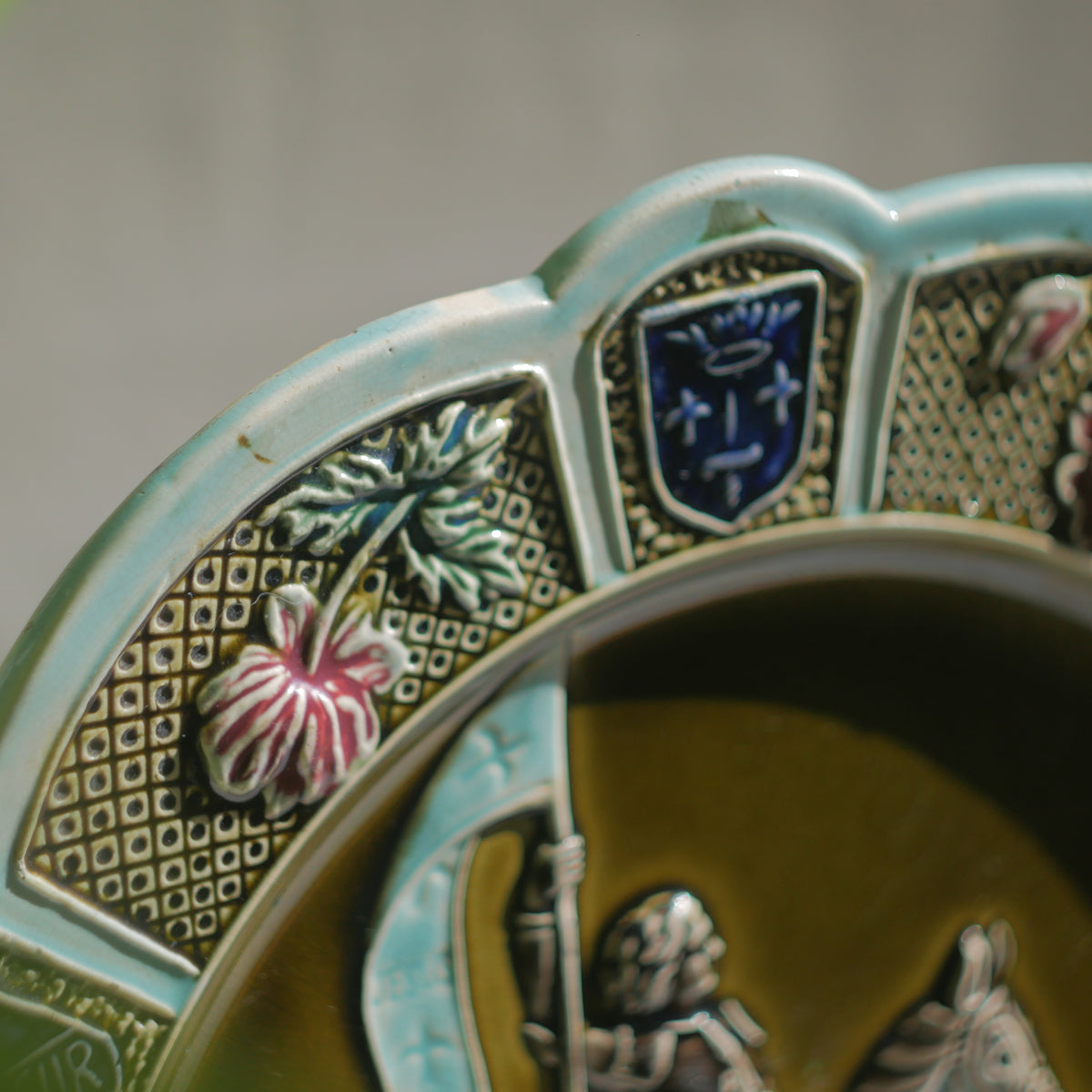 A large vintage/antique majolica wall plate with hand-coloured details in relief, the theme of the plate being the Patron Saint of France - Joan of Arc riding into battle with her banner (in French she is called Jeanne D'Arc).

This wonderful French decorative plate has a rich gloss finish, the glaze even being applied to the underside.

Around the lightly scalloped circumference of this large plate are patriotic symbols such as 'En Avant' (Go Forward), 'Honneur' (Honour) and 'Patrie' (Homeland).