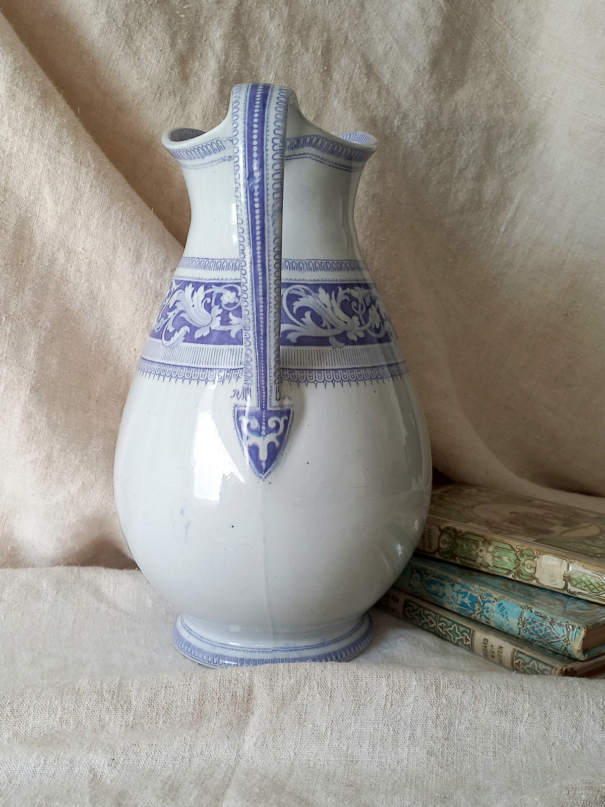 Antique ironstone pitcher in white with a rare lavender colour decorative pattern in a decorative setting.