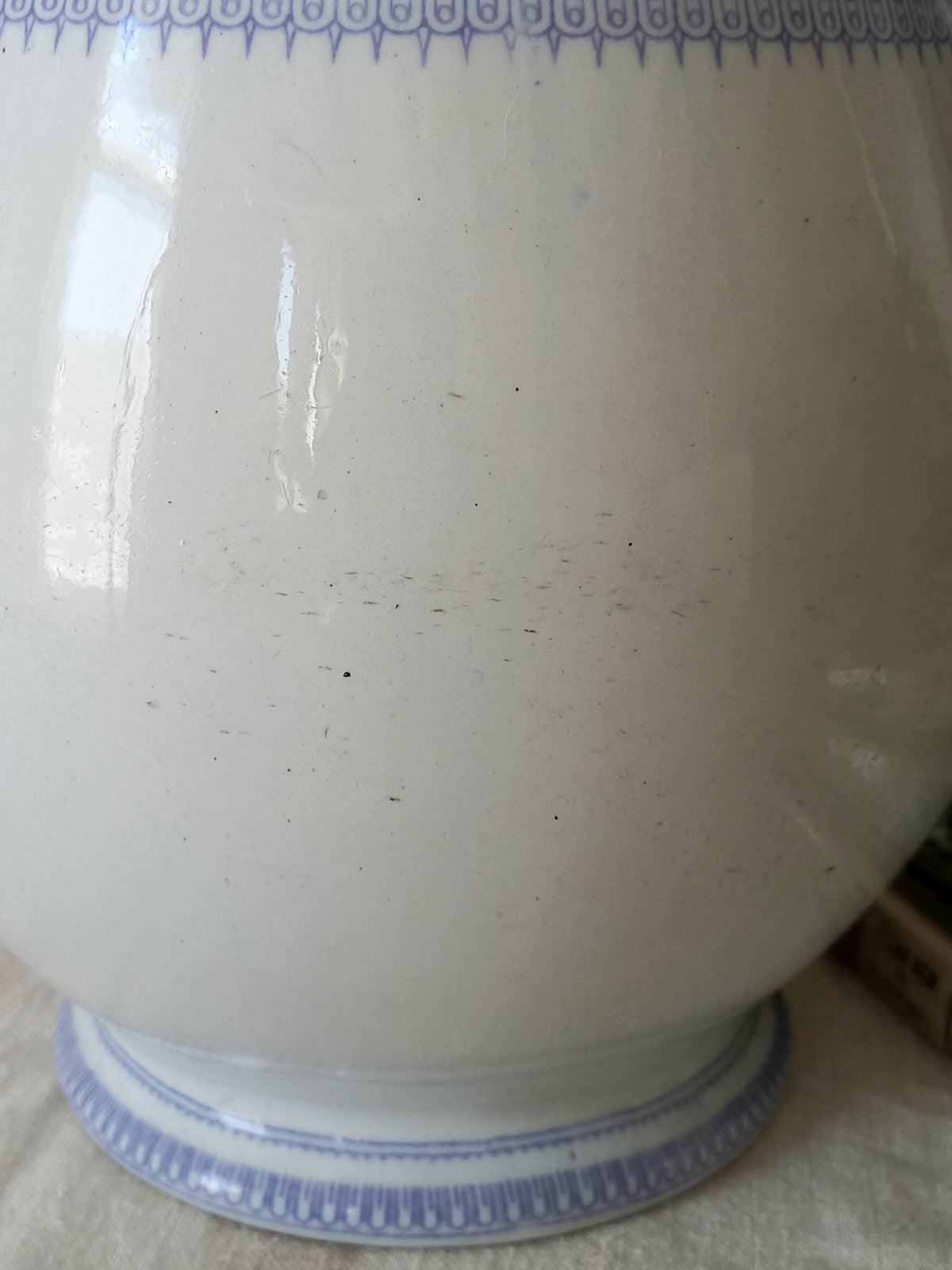 Close-up of an antique ironstone pitcher in white with a rare lavender colour decorative pattern in a decorative setting.