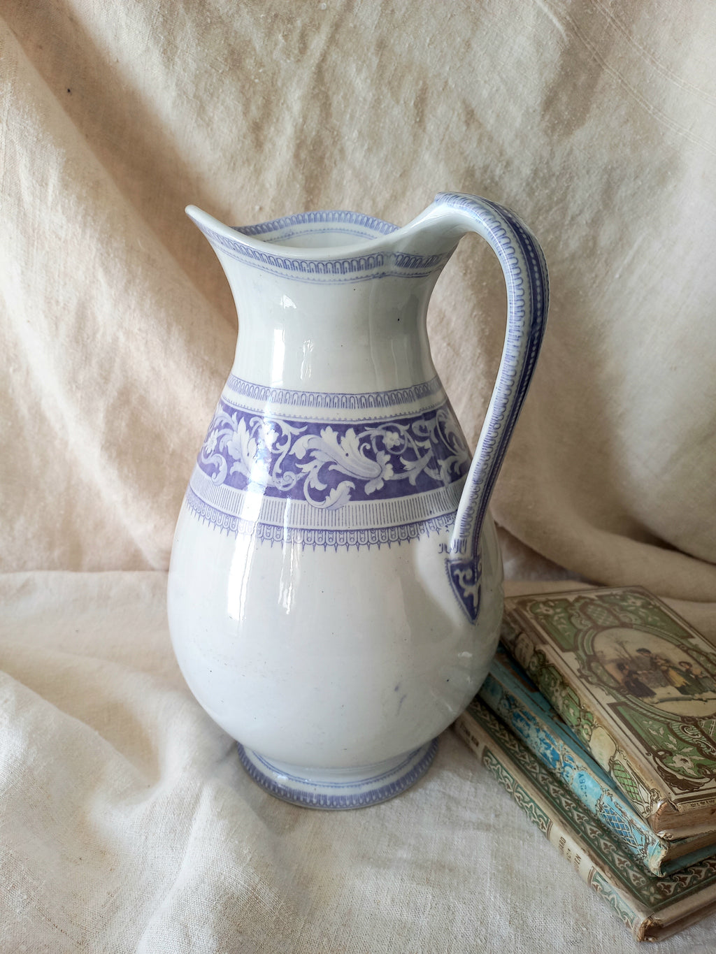 Antique ironstone pitcher in white with a rare lavender colour decorative pattern in a decorative setting.