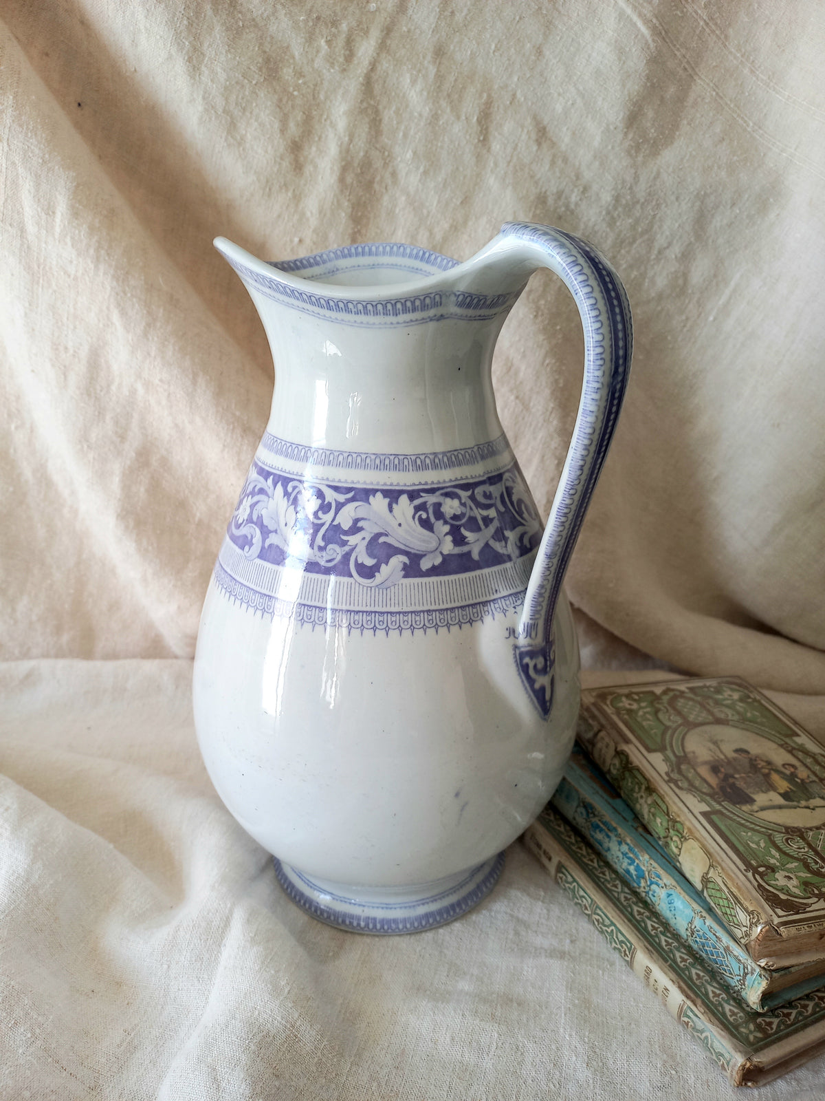 Antique ironstone pitcher in white with a rare lavender colour decorative pattern in a decorative setting.