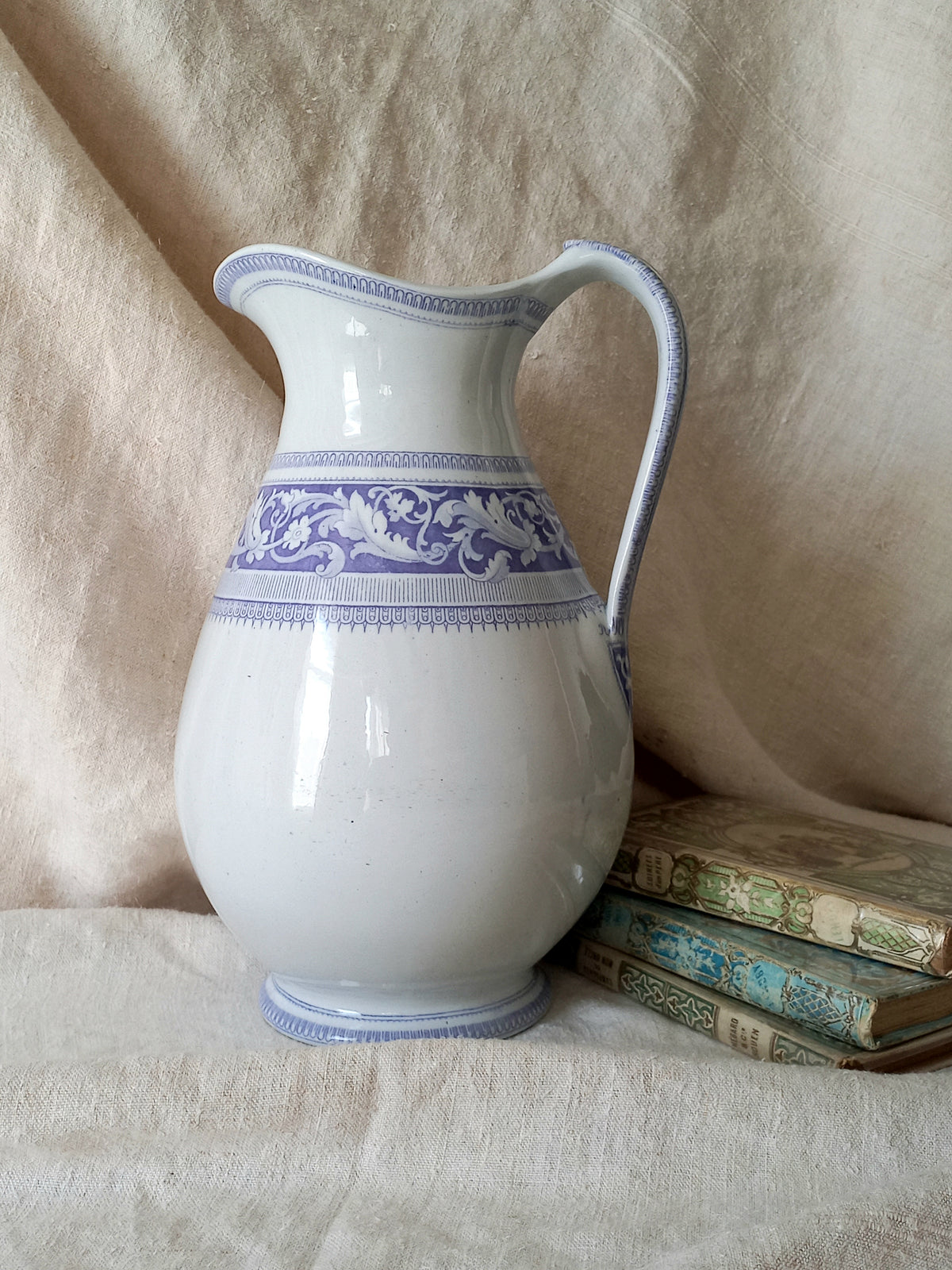 Antique ironstone pitcher in white with a rare lavender colour decorative pattern in a decorative setting.