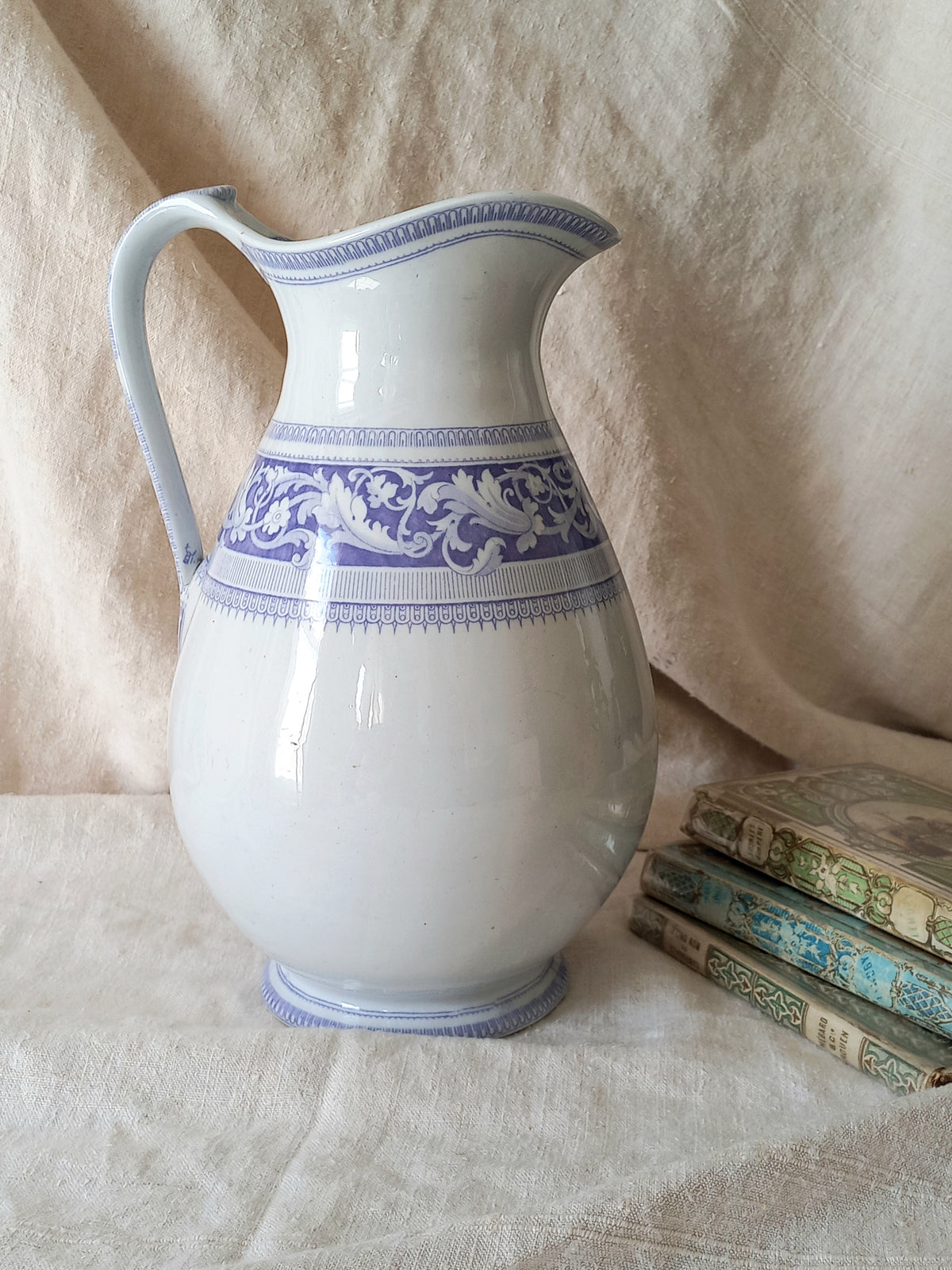 Antique ironstone pitcher in white with a rare lavender colour decorative pattern in a decorative setting.