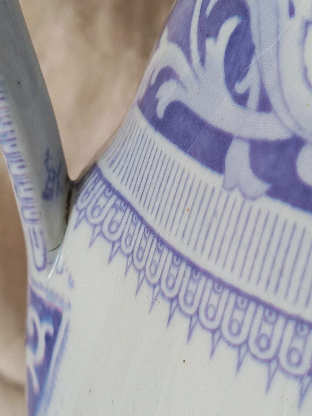 Close-up of a antique ironstone pitcher in white with a rare lavender colour decorative pattern in a decorative setting.