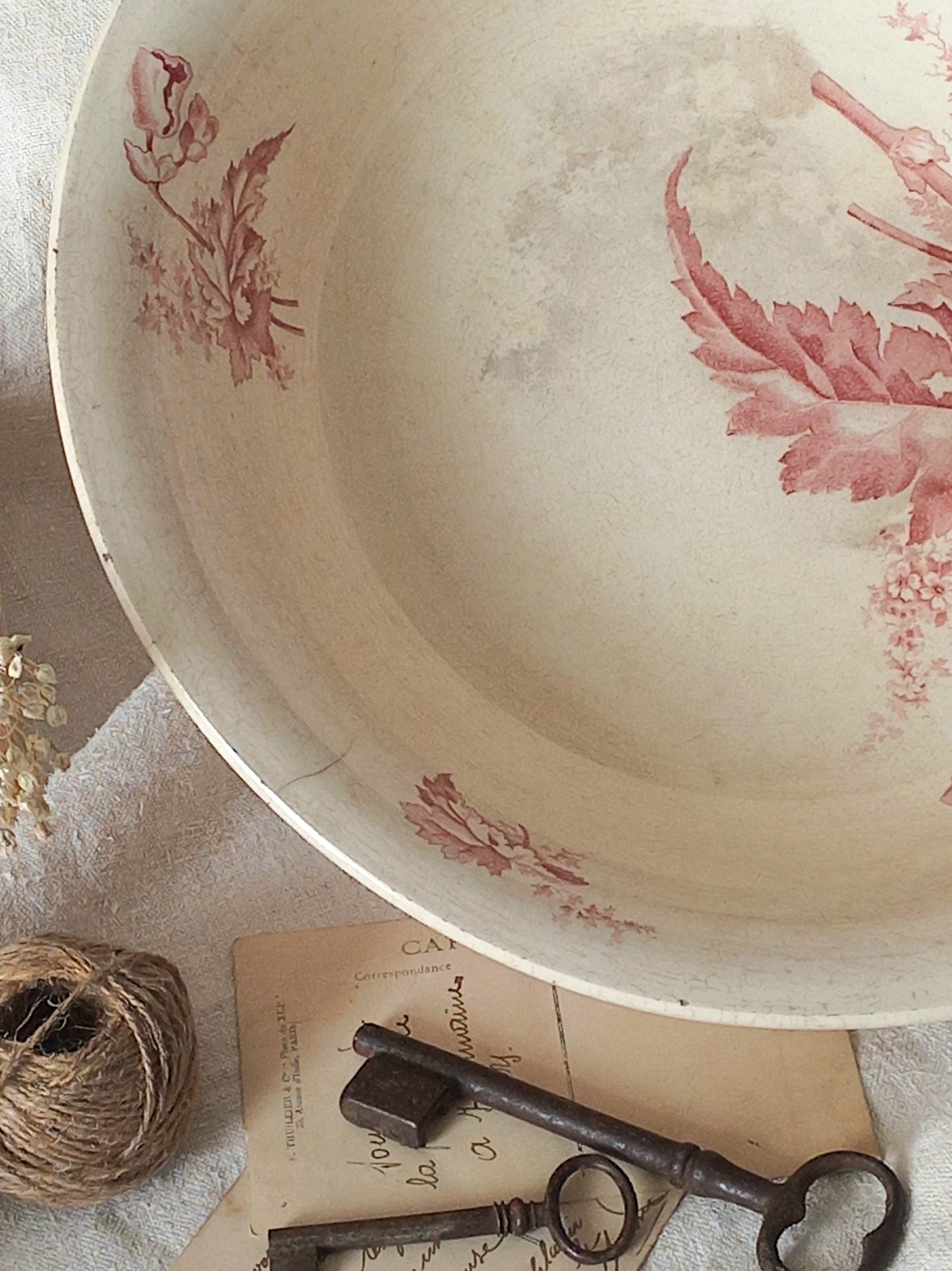 A large French ironstone bowl with deep pink floral pattern on a creamy white base. This antique piece has aged naturally over time, showing fine crazing, tea-staining, and small imperfections that reflect its long history.