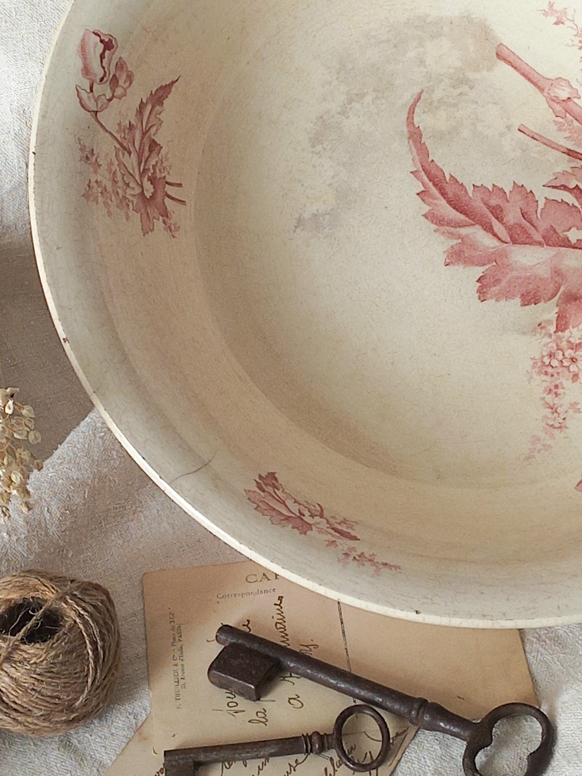 A large French ironstone bowl with deep pink floral pattern on a creamy white base. This antique piece has aged naturally over time, showing fine crazing, tea-staining, and small imperfections that reflect its long history.