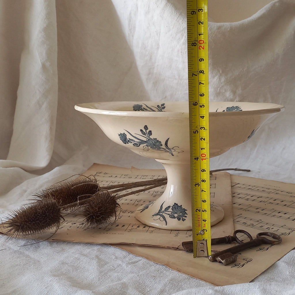 A beautiful antique compote or footed bowl by French manufacturer Longchamp. The main colour is a warm cream/white with blue floral transferware pattern.