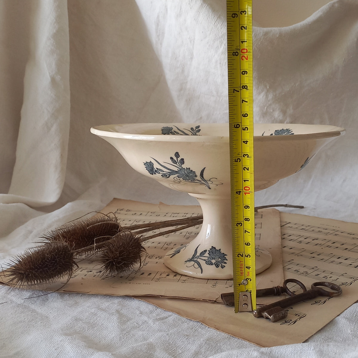 A beautiful antique compote or footed bowl by French manufacturer Longchamp. The main colour is a warm cream/white with blue floral transferware pattern.