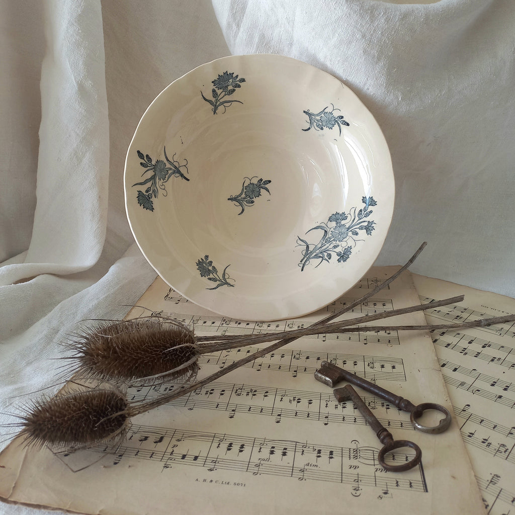 A beautiful antique compote or footed bowl by French manufacturer Longchamp. The main colour is a warm cream/white with blue floral transferware pattern.