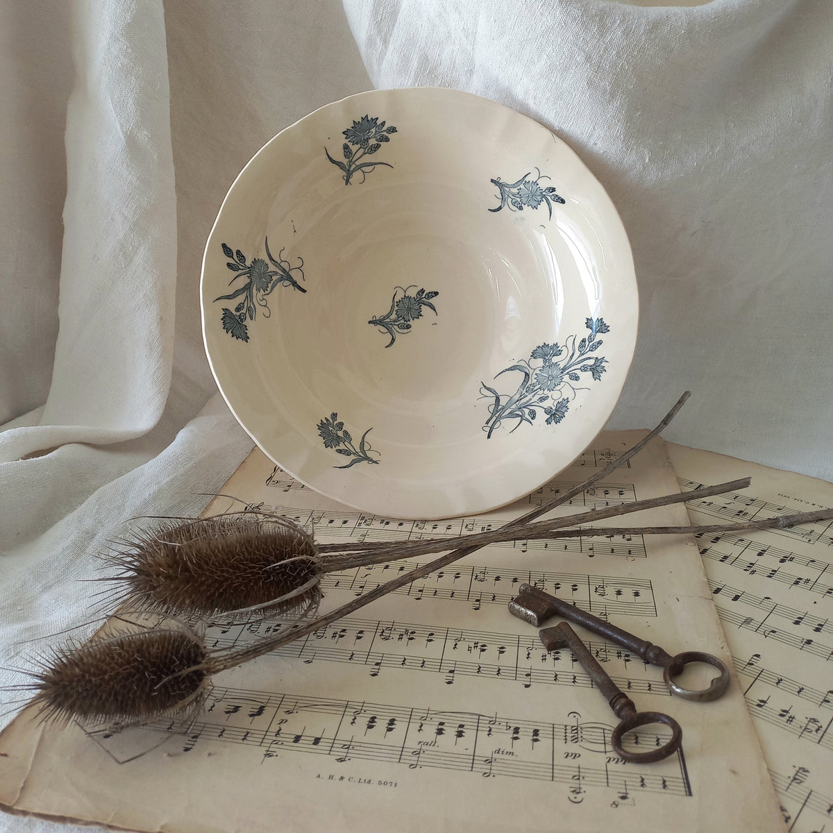 A beautiful antique compote or footed bowl by French manufacturer Longchamp. The main colour is a warm cream/white with blue floral transferware pattern.