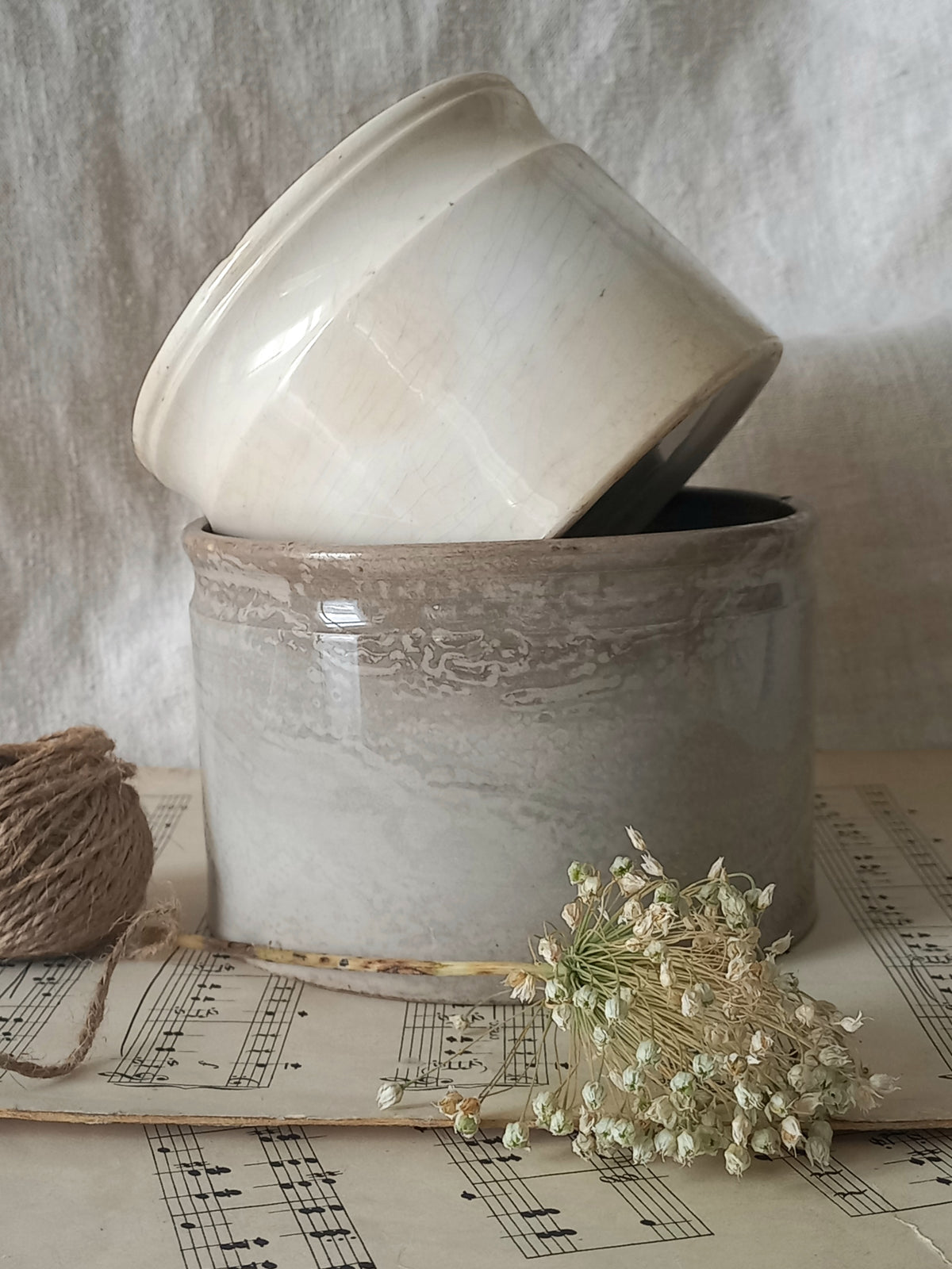 Two ceramic pots on a sheet of music with dried flowers and twine.