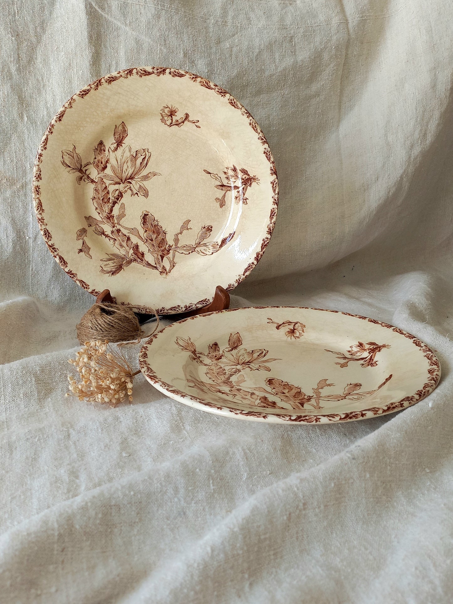 Two ceramic plates with floral patterns on a textured fabric background