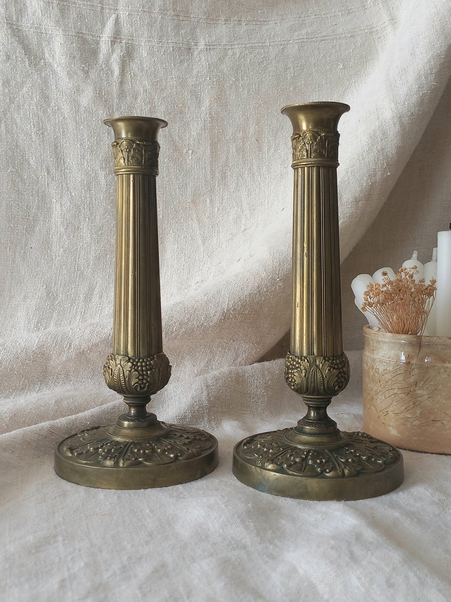 Pair of beautiful French antique decorative candle holders with Empire styling on a beige background.
