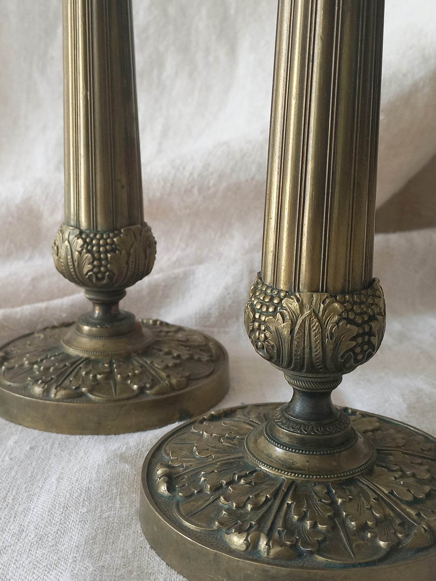 Detail of a pair of beautiful French antique decorative candle holders with Empire styling on a beige background.