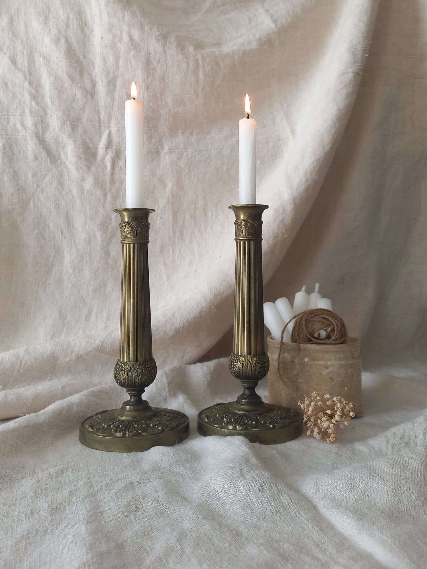 Pair of beautiful French antique decorative candle holders with Empire styling on a beige background.