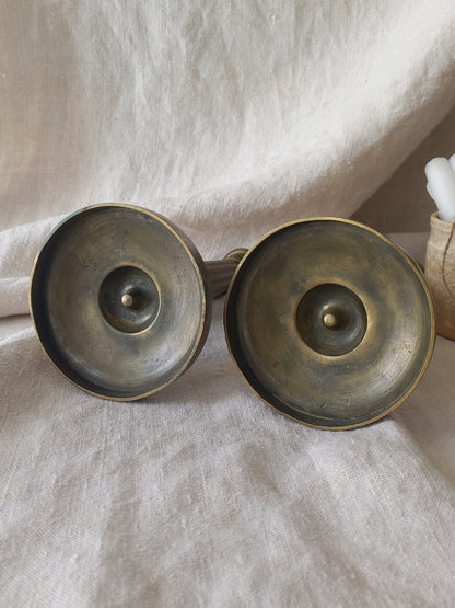 Pair of bronze candle holders on a textured fabric background