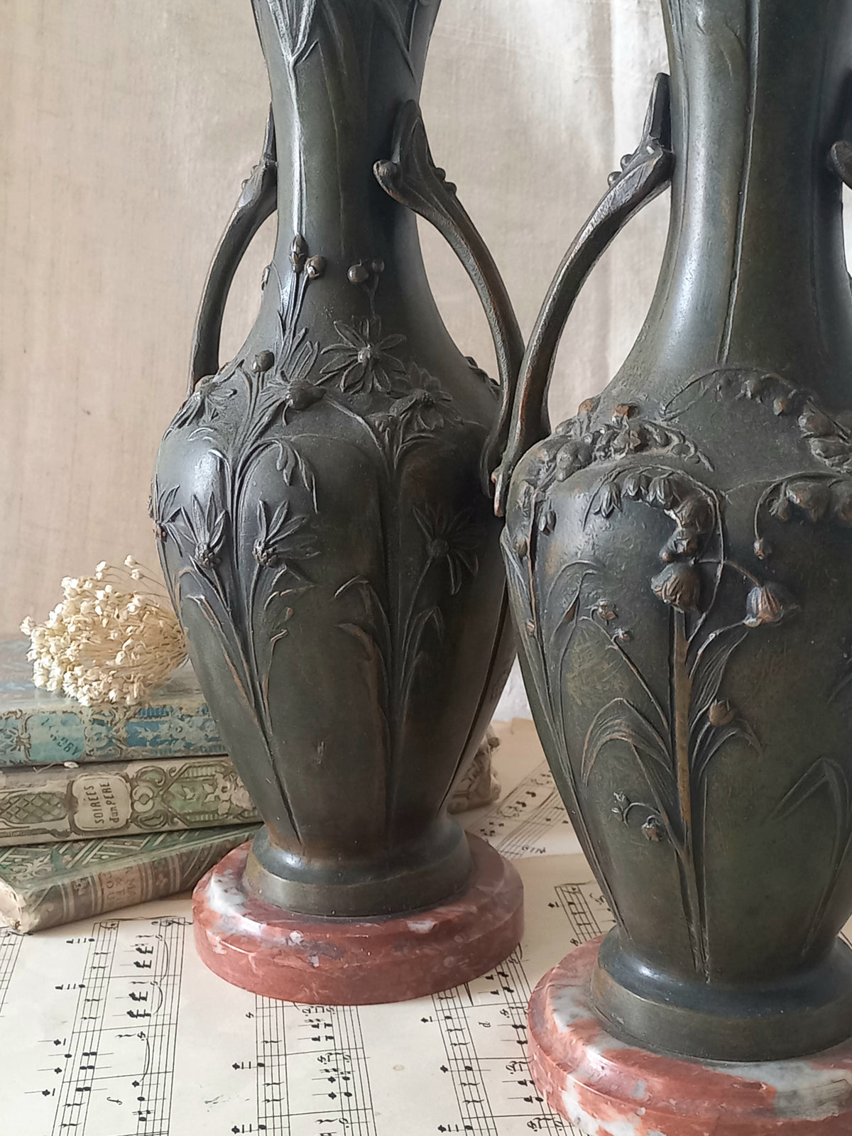 A stunning pair of decorative art nouveau vase/urn ornaments made from metal and finished in a stunning shade of green depicting organic floral decoration in relief.