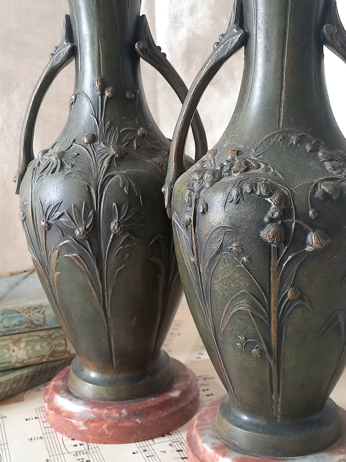A stunning pair of decorative art nouveau vase/urn ornaments made from metal and finished in a stunning shade of green depicting organic floral decoration in relief.