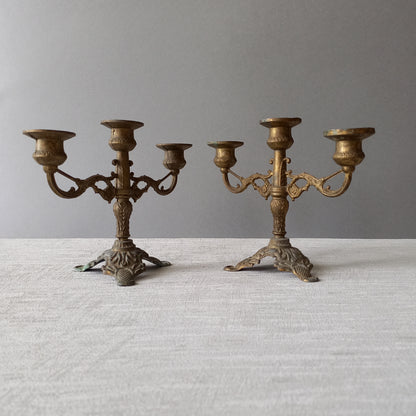 A pair of small vintage antique metal candelabras. This pair of decorative candle stick holders will give that touch of French shabby chic to any interior.