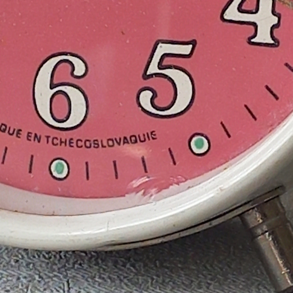 A wonderful vintage alarm clock in an eye-catching white and pink color scheme. This old clock is in working condition including the alarm and has a nice soothing ticking sound too. A great piece of European history from the former country of Czechoslovakia.