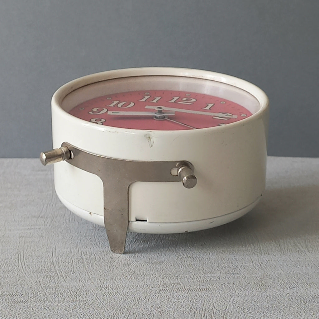 A wonderful vintage alarm clock in an eye-catching white and pink color scheme. This old clock is in working condition including the alarm and has a nice soothing ticking sound too. A great piece of European history from the former country of Czechoslovakia.