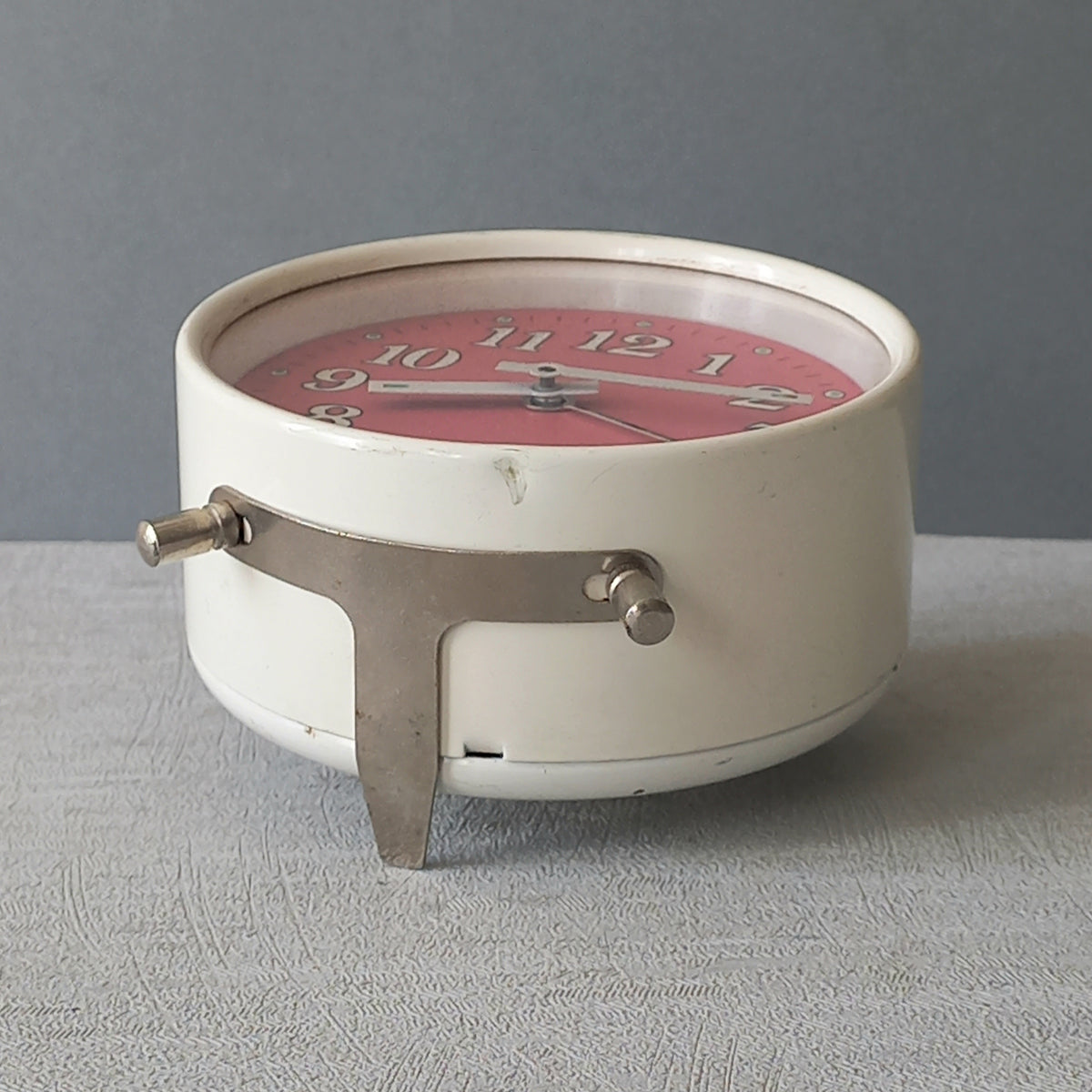 A wonderful vintage alarm clock in an eye-catching white and pink color scheme. This old clock is in working condition including the alarm and has a nice soothing ticking sound too. A great piece of European history from the former country of Czechoslovakia.