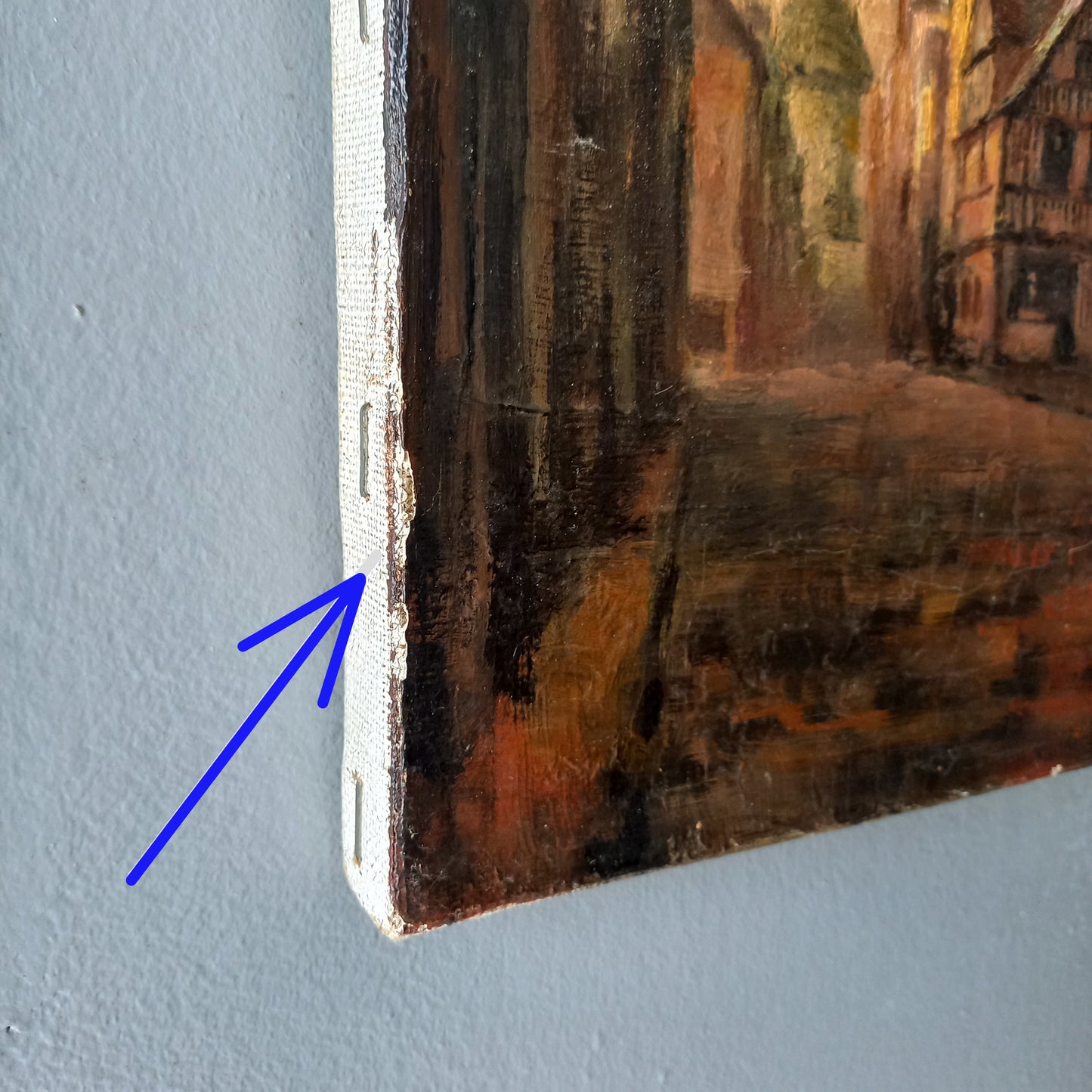 Close-up of a painting corner with a blue arrow pointing to a small rectangular object.