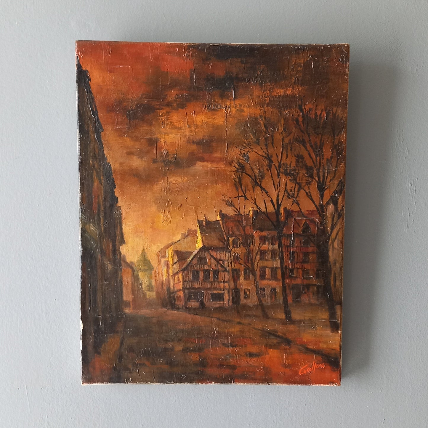 Painting of a street scene with buildings and trees on a gray wall