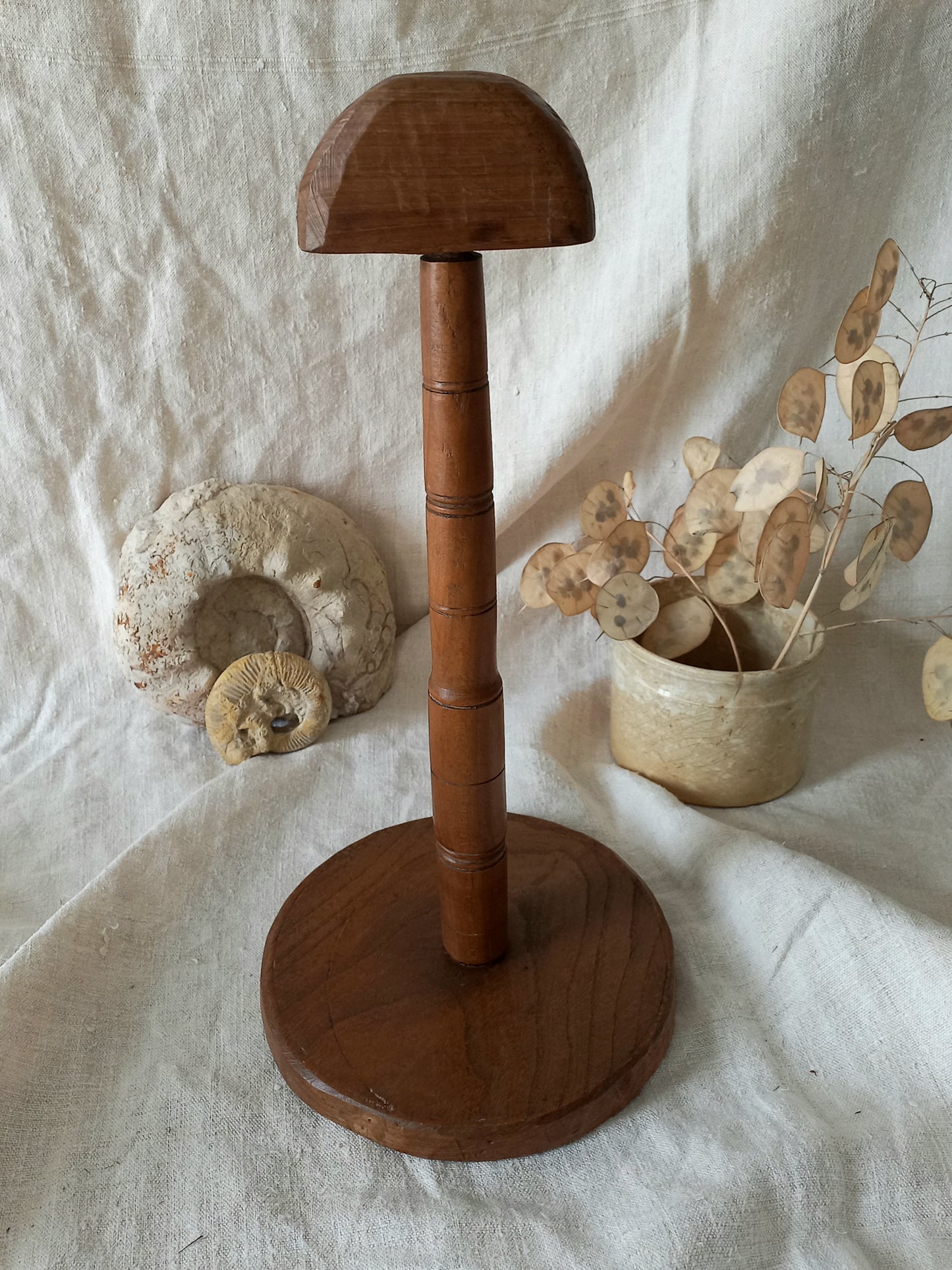 vintage wooden hat stand on a textured white fabric background