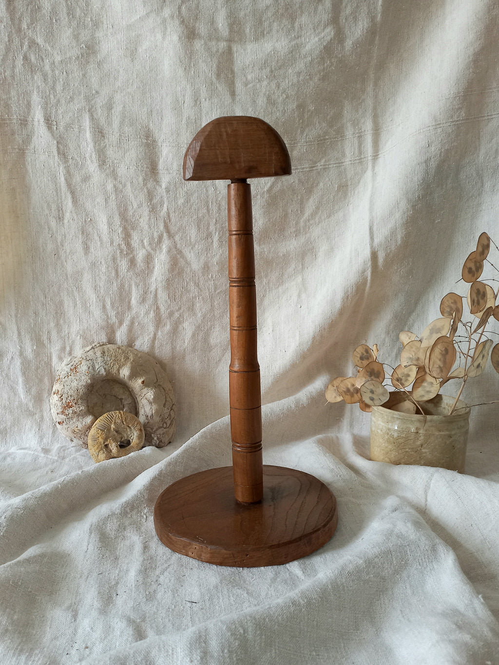 vintage wooden hat stand on a textured white fabric background