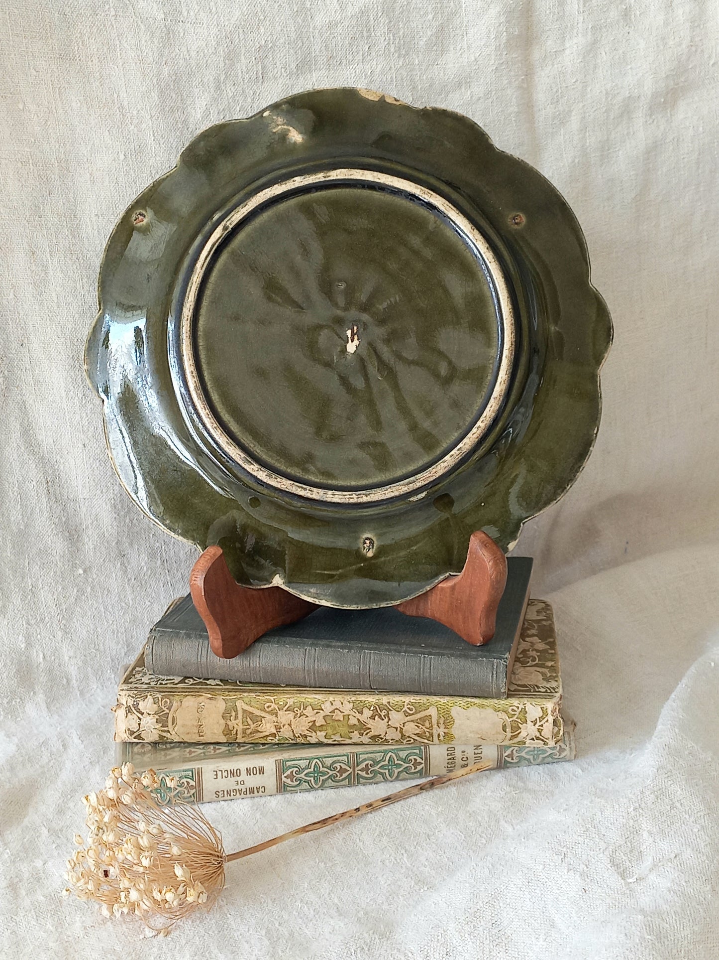 Rear of decorative plate with a scene of Joan of Arc on a horse, surrounded by decorative elements on a white background.