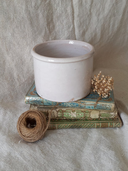antique jam pot on a textured surface, dried flowers, and books on a textured surface