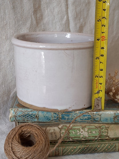 antique jam pot on a textured surface, dried flowers, books on a textured surface and a tape measure for reference.