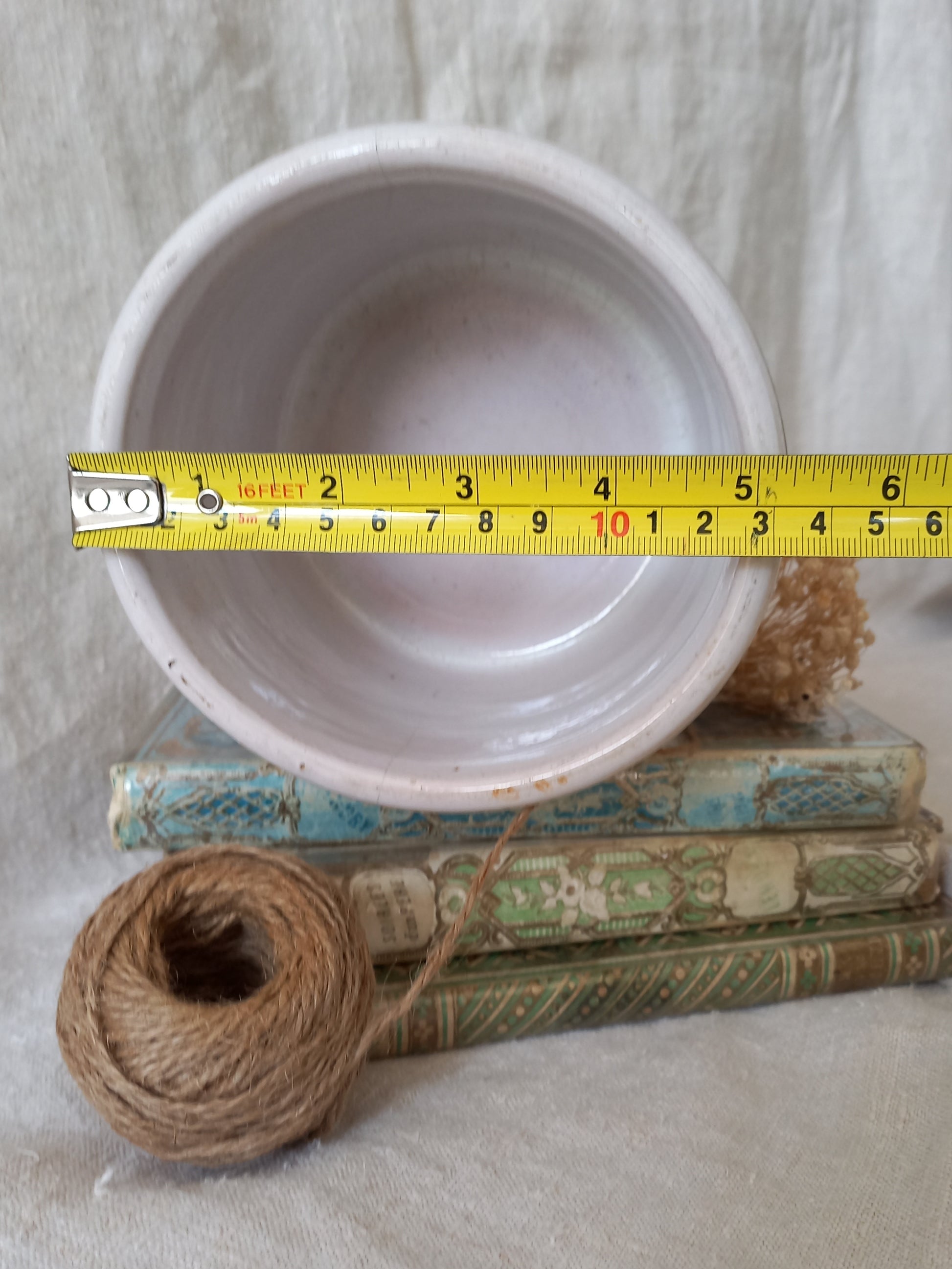 White antique jam pot on top of vintage books with a measuring tape