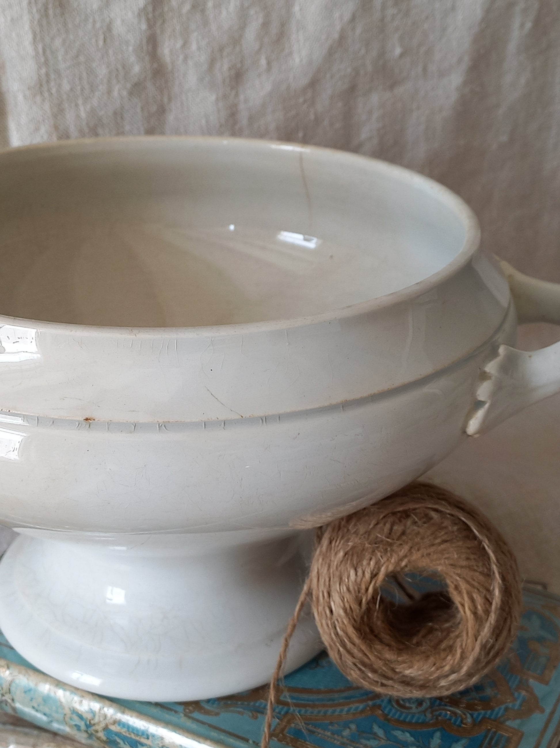 White ceramic bowl with a ball of twine on a textured surface
