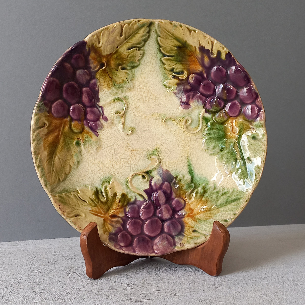 Small and beautiful French antique crazed majolica plate with a wonderful colour scheme depicting dark purple grapes and green foliage; this wonderful old plate will make an excellent addition to a collection or as a stand-alone display piece.
