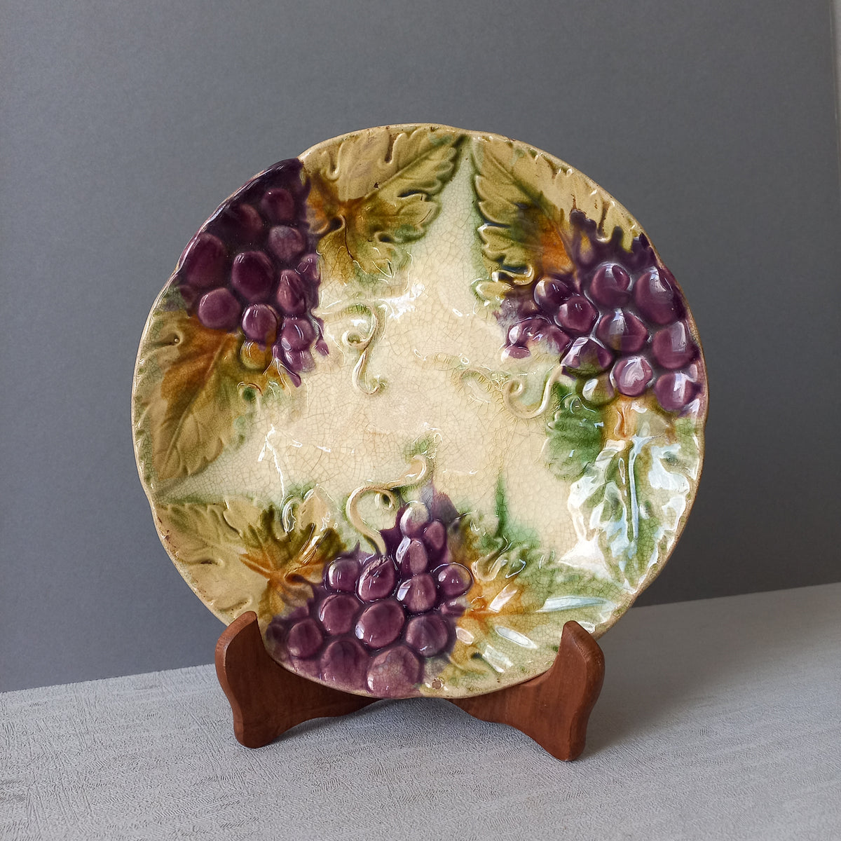 Small and beautiful French antique crazed majolica plate with a wonderful colour scheme depicting dark purple grapes and green foliage; this wonderful old plate will make an excellent addition to a collection or as a stand-alone display piece.