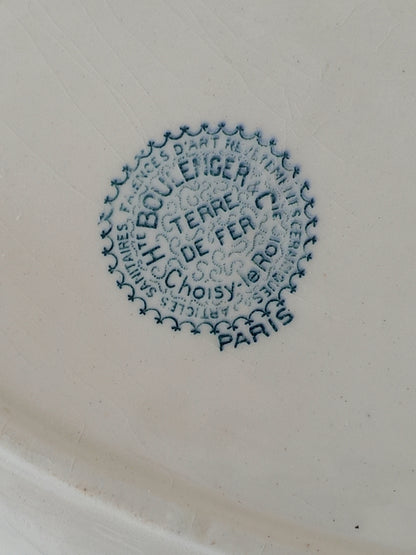 Close-up of a white ceramic surface with a blue circular manufacturer's mark .