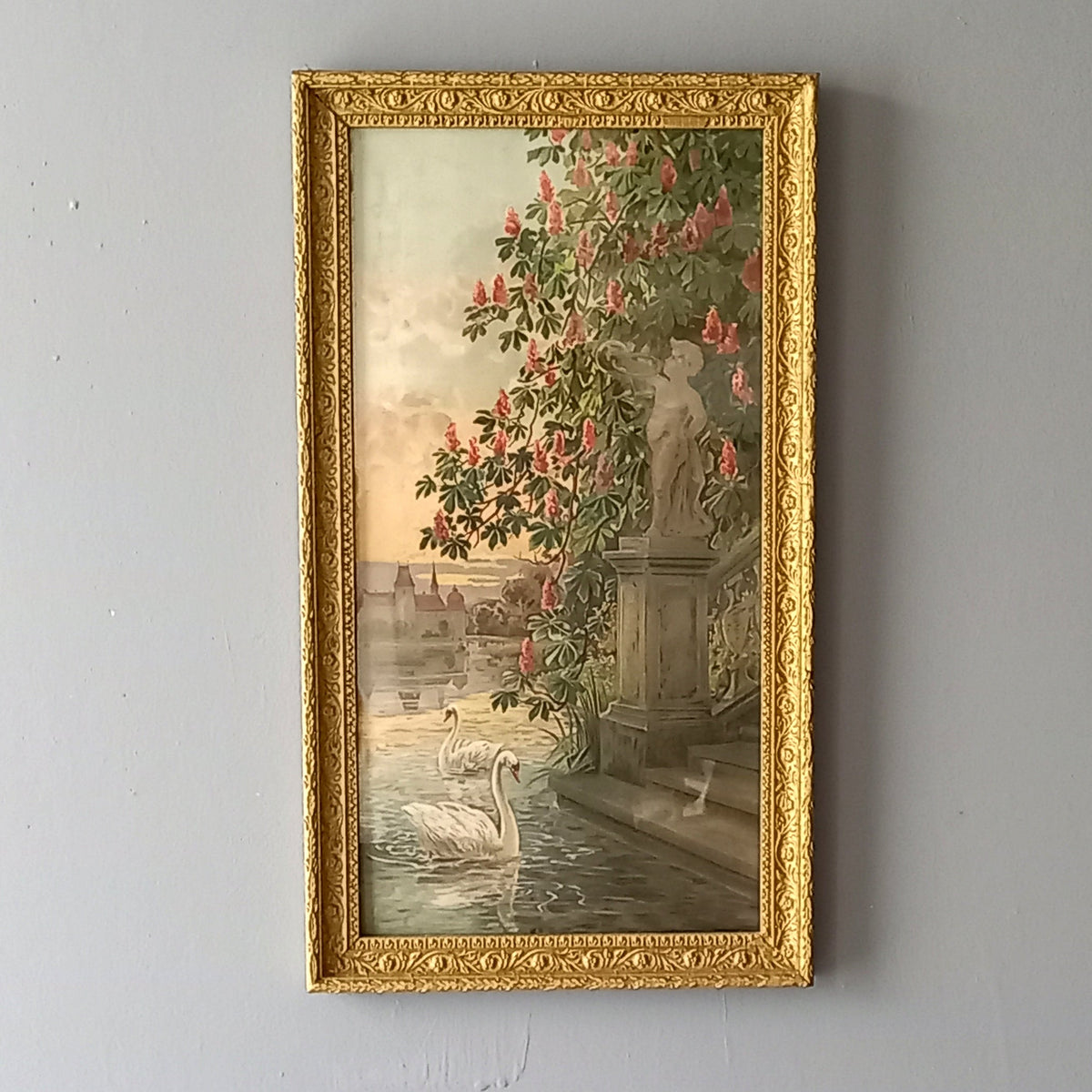 Decorative painting with a gold frame featuring a classical scene with swans and flowers on a gray wall.